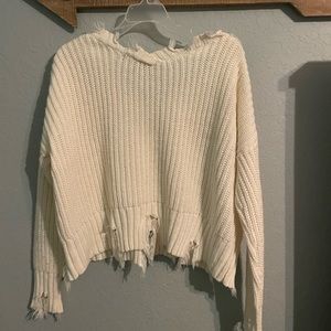 A white knitted sweater in the size medium.